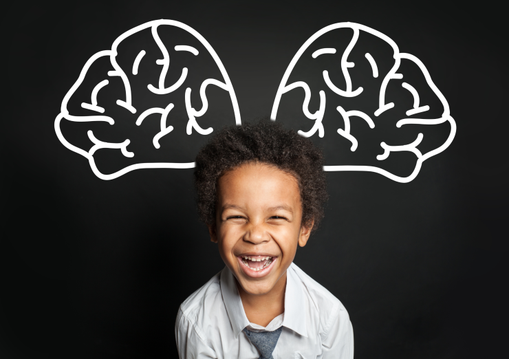 boy smiling with a chalk drawing of a brain behind him
