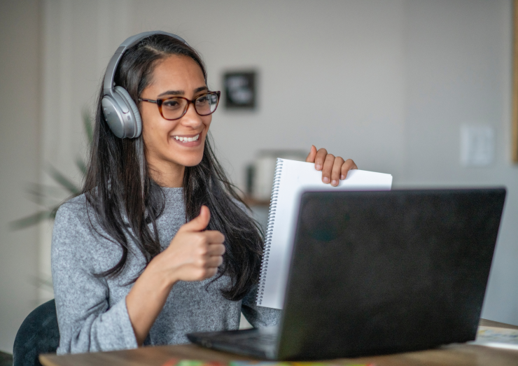 Woman smiling at screen holding thumbs up