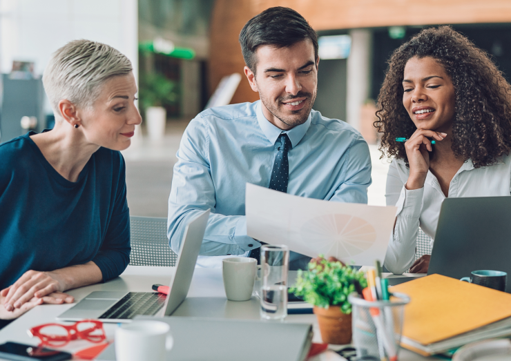 three people looking at a research paper